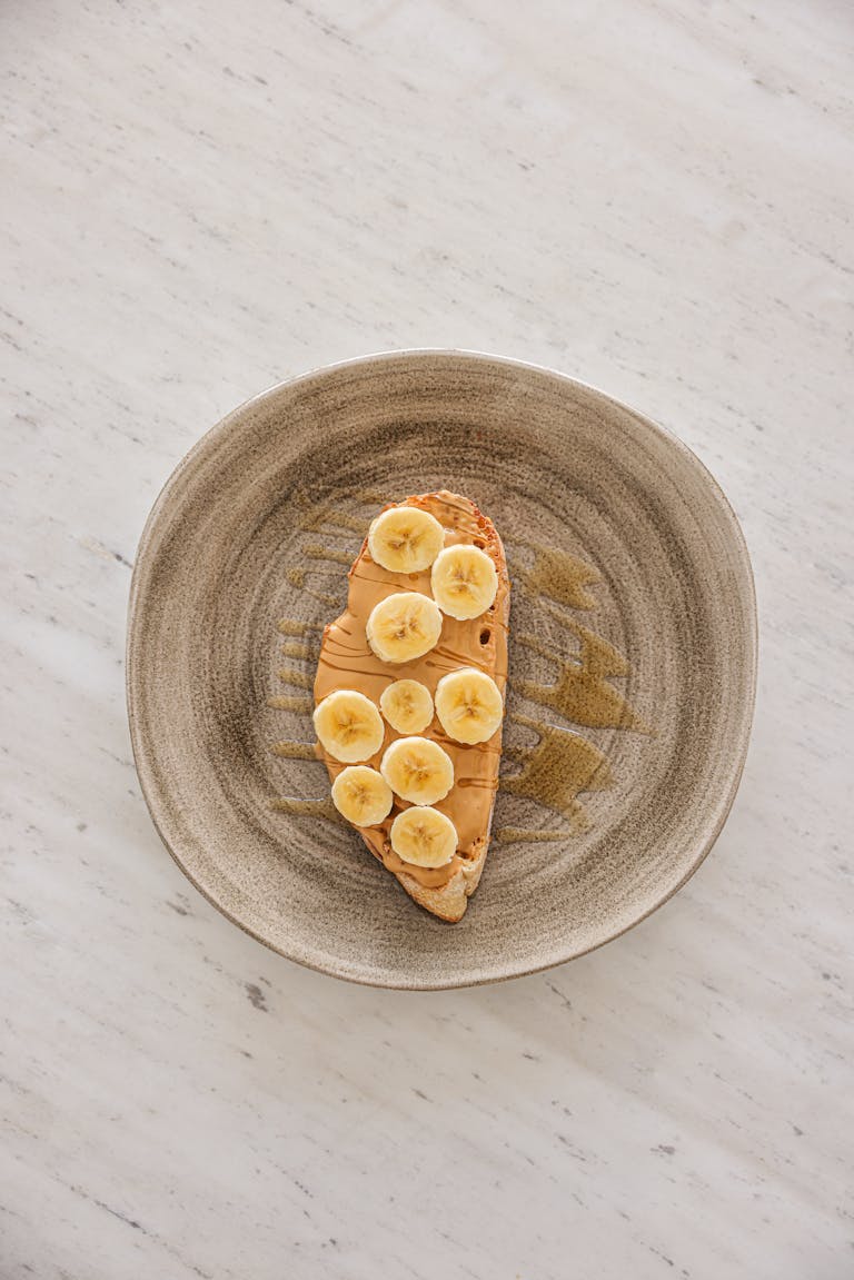High-angle shot of banana slices on peanut butter toast on a plate.