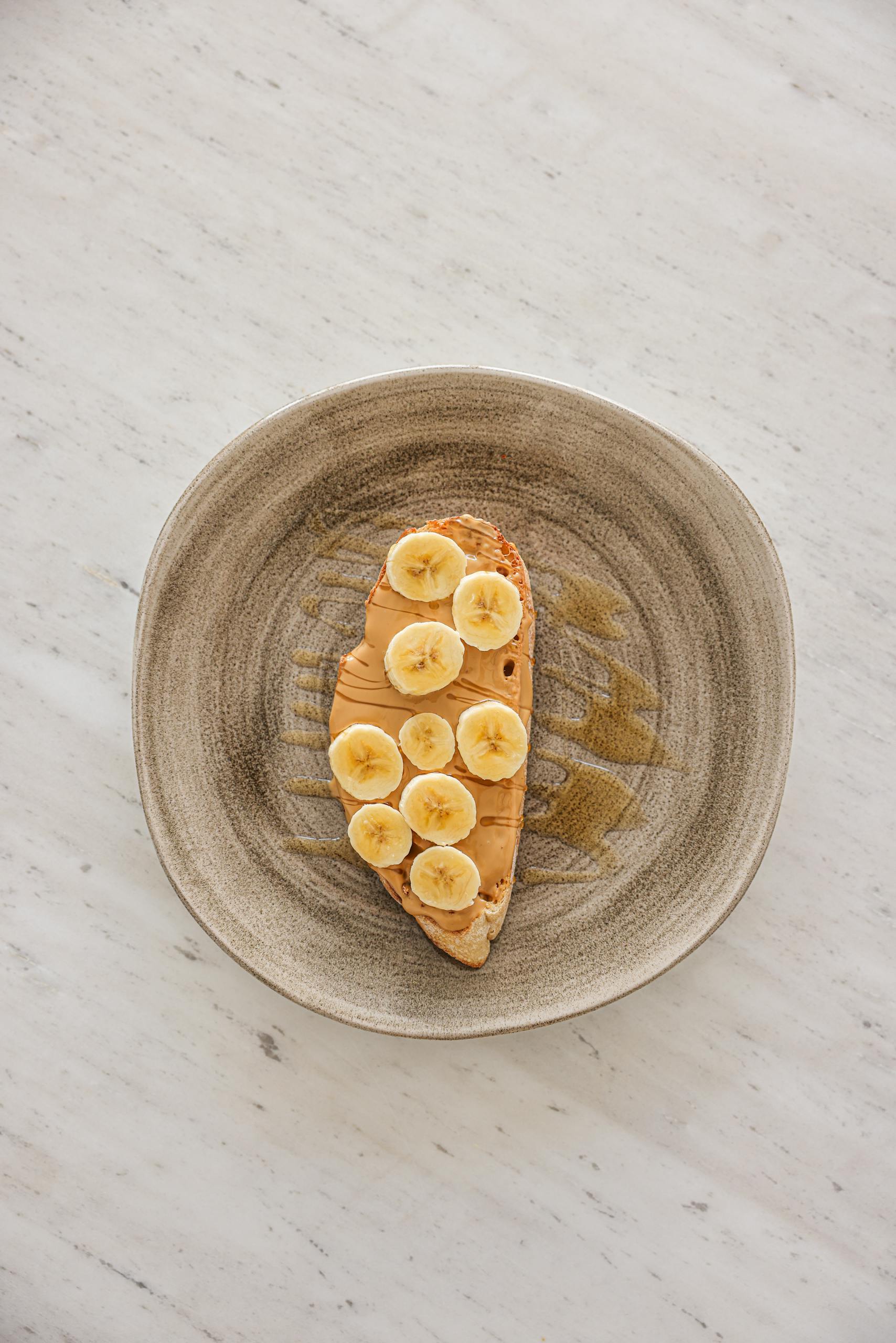 High-angle shot of banana slices on peanut butter toast on a plate.